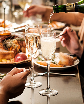 Close up of family sitting around a holiday meal, champagne being poured.